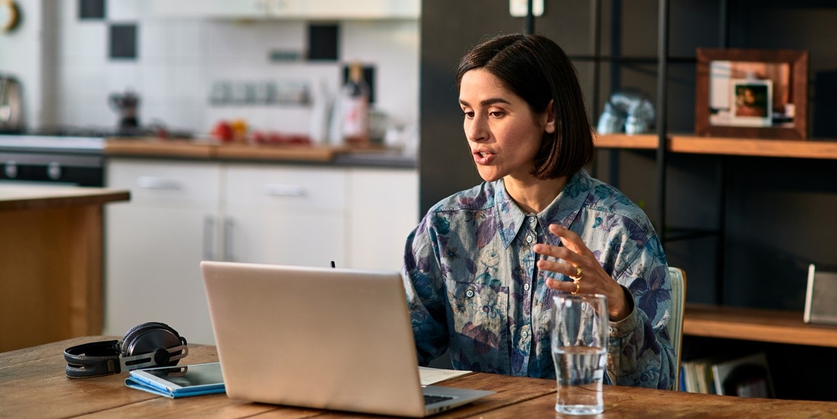 mujer en oficina trabajando en laptop, junta virtual