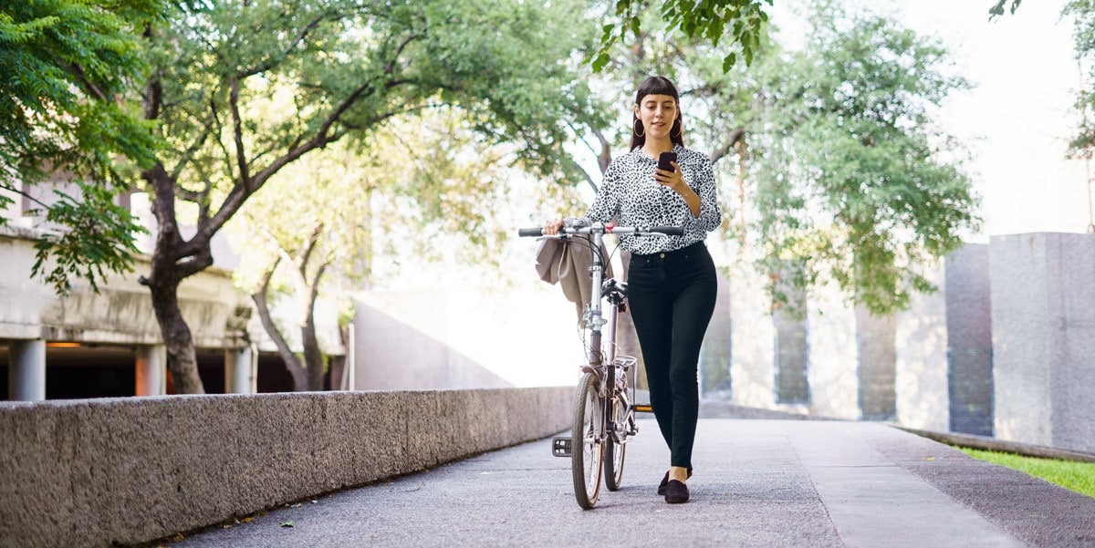 woman with bicycle outdoors, using cellphone