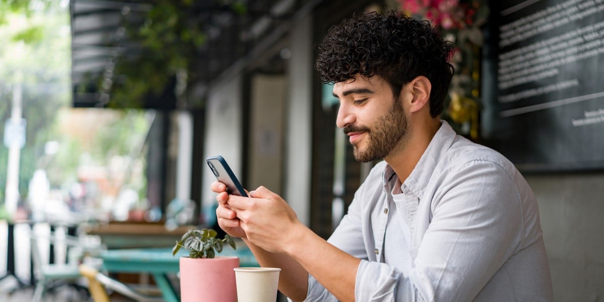 man using phone at a cafe