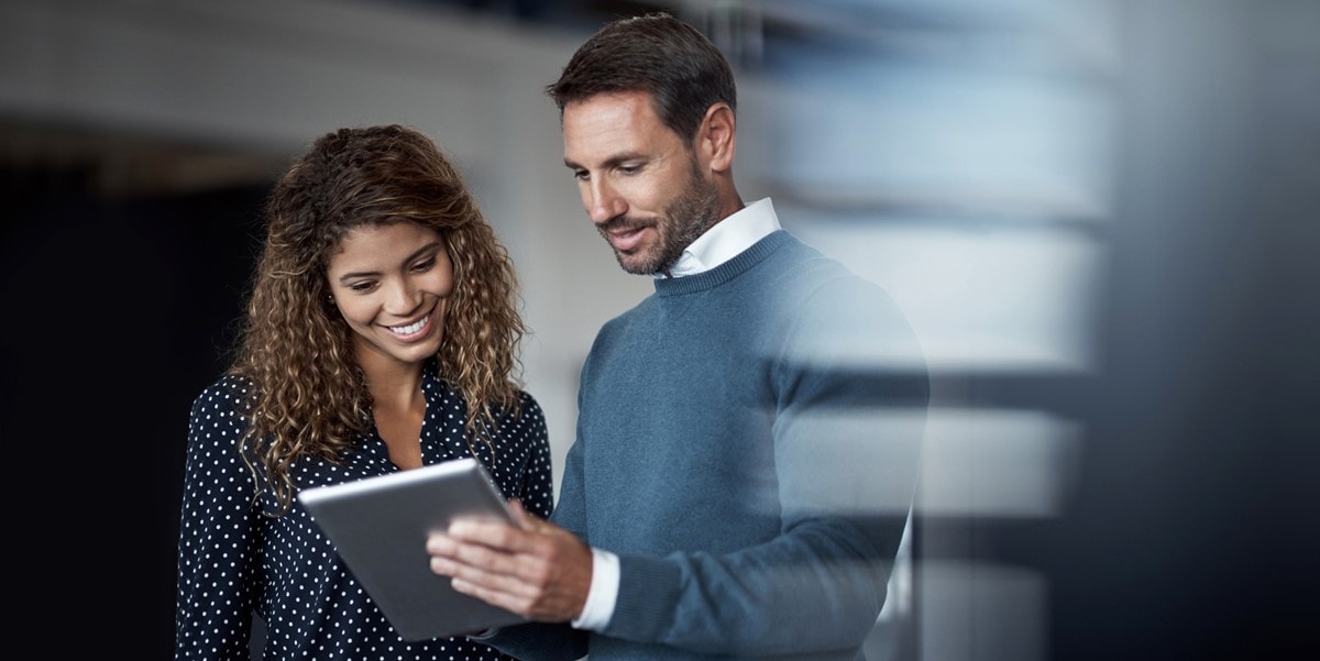 two professional in office looking at a tablet