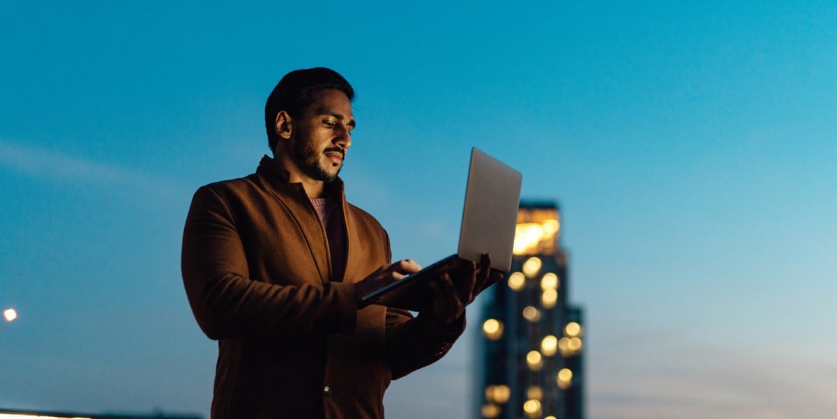 man holding laptop outdoors