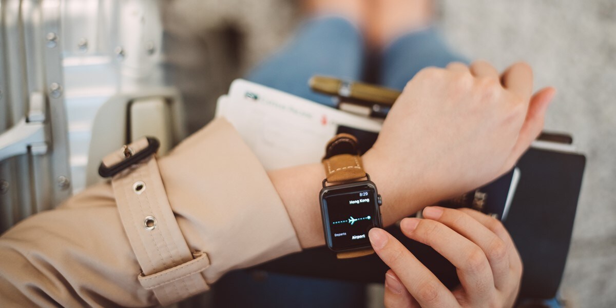 traveler sitting with suitcase, focus on watch and travel documents in hand